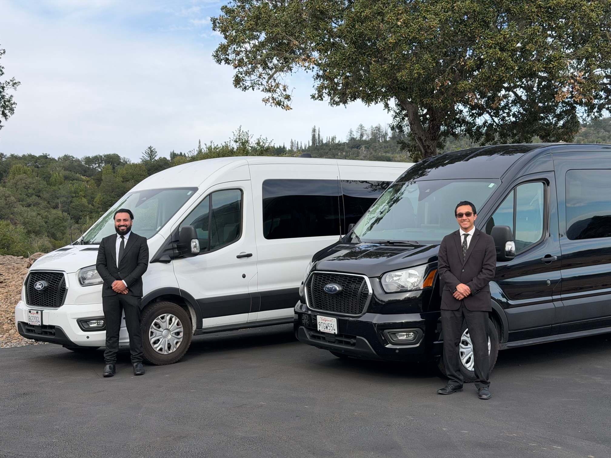 HTH chauffeurs in tailored suits standing beside the white and black luxury shuttle vans at a Wine Country estate